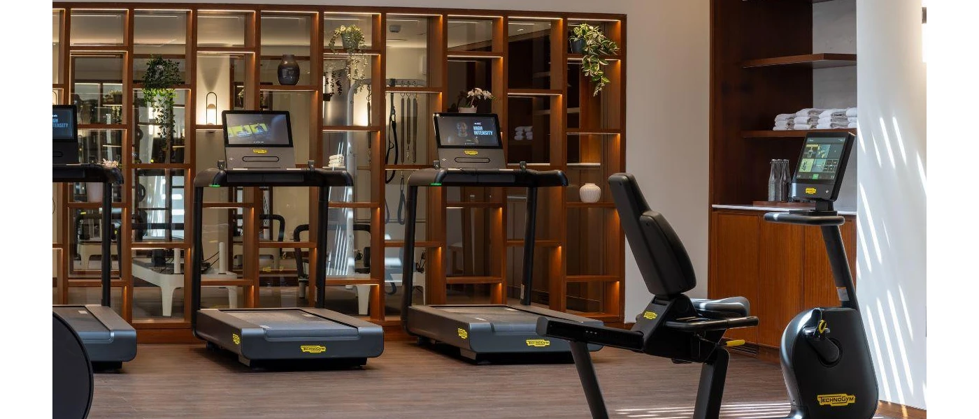 Treadmills with screens in a gym with wooden furnishings and spotlights
