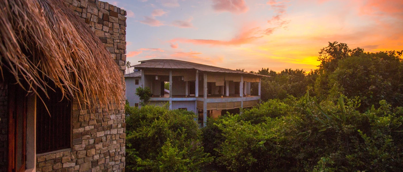 Stone buildings among the rainforest as the sun sets in the sky above