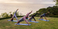 Group yoga fitness class practicing on a terrace with sea view.