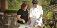 Chef and guest work together over an al fresco kitchen table set-up as part of a cooking workshop