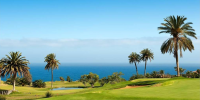 Lush green golf course at Hacienda del Conde, Tenerife, set against a backdrop of volcanic hills and blue skies