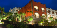 Perimeter of Hacienda del Conde, Tenerife, lit up at night with glowing lights and silhouetted palm trees