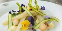 Plate of vegetables garnished with purple and yellow edible flowers