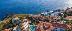 Sentido Galosol from above, including its oceanfront location, swimming pool, palm trees and terracotta-roofed buildings