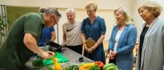 Group of women watching a chef prepare ingredients in a kitchen workshop