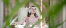 Smiling woman relaxes in headphones with her eyes closed, while sitting back and being treated with a drip