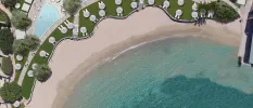 Aerial view of a swimming pool, lawn with loungers and parasols, sandy beach and the sea