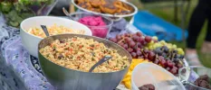 A selection of food in large bowls next to a fruit platter