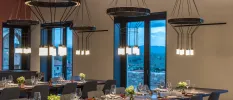 Modern restaurant with long communal tables, floor-to-ceiling windows, greige walls and modern pendant lights