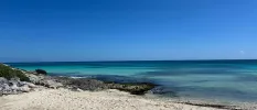 White sandy beach with turquoise shallows under a bright clear blue sky