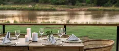 Table laid up with glassware, white napkins and candles with a view of the riverbank