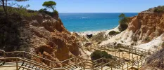Wooden steps and walkway down to a golden sandy beach, sandwiched by cliffs