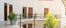 Two storeys in a white building with wooden doors and potted plants