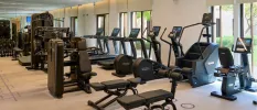 Bikes, steppers, benches and weight machines in a well-equipped gym with floor-to-ceiling windows