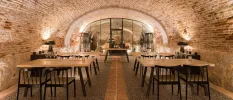 Underground wine cellar and tasting area, with stone walls, wooden tables and chairs, and empty glasses ready for guests