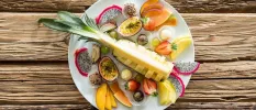 White plate piled with fruit including pineapple, peaches and strawberries