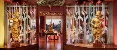 Dark-wood restaurant entrance with two matching gold statues and the words 'The Oriental' etched above the door
