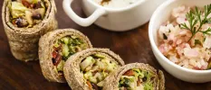 Wraps filled with colourful vegetables and a bowl of rice in close-up