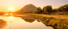 Olifants River in South Africa, with grassy banks and leafy hills in the background at sunset