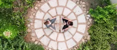 Two women in active wear sit in meditative poses in a stone circular terrace