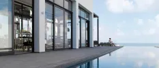 Infinity pool looking over the ocean next to a contemporary glass-windowed white building