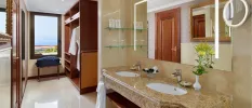 Bathroom with marble-look vanity with a large LED-lit mirror and dual sinks, a dressing area with a wooden wardrobe and bathrobes hanging inside