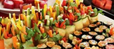 A platter of food including sushi and vegetables wrapped in cucumber