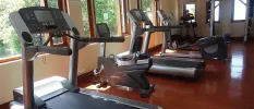 Treadmills in a gym with a shiny floor and windows overlooking tropical greenery