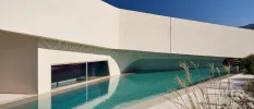 Futuristic looking angular building with a window and wedge-shaped swimming pool next to it