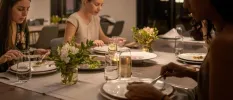 Group enjoy a meal in a softly lit restaurant with vases of white flowers on the table