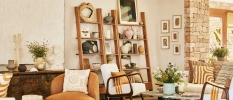 White-walled room with stone finishes, wooden shelving with ornaments, terracotta seating and potted plants