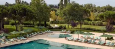 Rectangular pool and circular swimming pool surrounded by green parasols, green and white striped cushions and lawned gardens