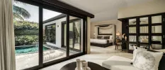 Stylish villa with a black and white colour scheme, a bed and living area and full-length patio doors the overlook a courtyard with a square pool
