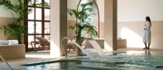 Woman in a white robe relaxing by the indoor pool at Hacienda del Conde spa, Tenerife