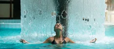 Woman in the thermal pool standing under a fountain of water