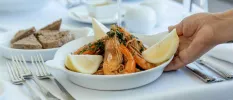 White tablecloth with plates of prawns, lemon slices and bread