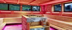 Wooden sauna  with pink LED lighting and windows with views of the greenery and mountains beyond