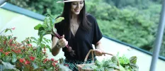 Smiling woman in a straw hat and black shirt holding organic vegetables
