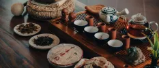 Wooden tray with a glass pot of tea, and various ingredients in bowls next to it