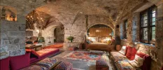 Cosy room with stone walls and ceiling, low-level patterned chairs and candlelight