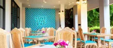 Light-wood tables and chairs with a blue statement wall that reads 'LOVE LIVE EAT'