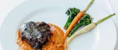 Grilled meat in a pumpkin-coloured sauce with broccoli and carrots