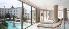 Indoor spa area with cream loungers and floor-to-ceiling windows overlooking a swimming pool