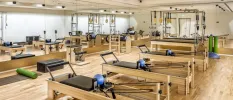 Reformer Pilates machines in a studio with wooden floors and full-size mirrors