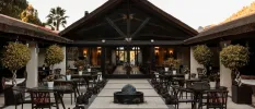 Courtyard with stone floors, a central black water fountain, black tables and chairs and surrounding potted trees
