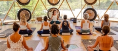 Group in active wear sit on purple mats and meditating
