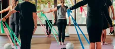Group in active wear take part in a class using yoga mats, colourful stretchy bands and medicine balls