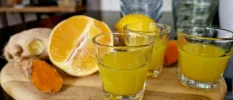 Glasses of juice next to lemons and ginger