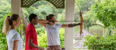 Two guests taking part in an archery activity as an instructor watches on