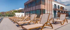 Contemporary building with wooden panelling overlooking rows of loungers on a patio terrace